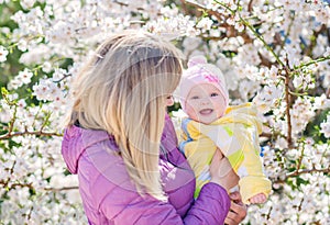 Mother hands throws up child in the blooming apple trees