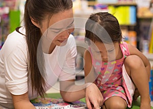 Mother is happily reading a book to her daughter in the bookstore