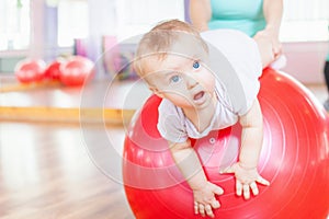 Mother with happy baby doing exercises with gymnastic ball