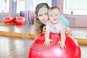 Mother with happy baby doing exercises with gymnastic ball