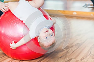 Mother with happy baby doing exercises with gymnastic ball