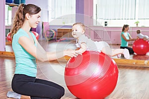 Mother with happy baby doing exercises with gymnastic ball