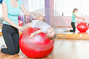 Mother with happy baby doing exercises with gymnastic ball