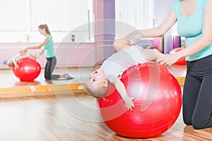 Mother with happy baby doing exercises with gymnastic ball