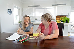 Mother and happy daughter studying at home during coronavirus self isolation and school closures