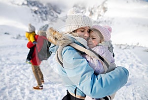 Matka so šťastnou malou dcérou v nosiči stojaca v zimnej prírode, odpočíva.
