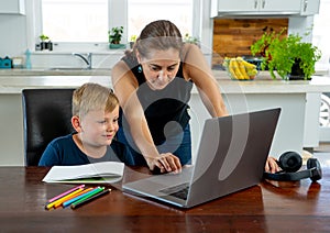 Mother and happy son studying at home during coronavirus self isolation and school closures