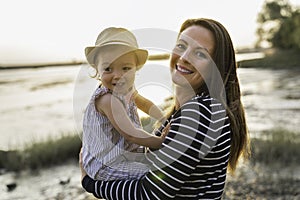 Mother have fun with baby on the beach at the sunset