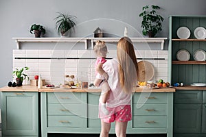 Mother having breakfast with her lovely daughter in the kitchen.