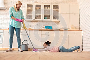Mother having fun with daughter while mopping the floor
