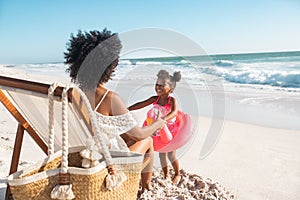 Mother having fun with her cute little girl with flamingo inflatable at beach