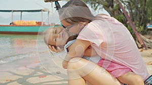 Mother having fun with her little cute daughter on hammock at the sandy beach