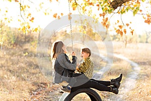 A mother is having fun with her little son sitting together on a swing wheel