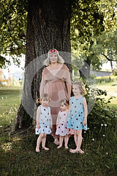 Mother having quality funny playing time with her baby girls at a park blowing dandelion - Young blonde hippie -
