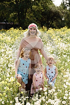 Mother having quality funny playing time with her baby girls at a park blowing dandelion - Young blonde hippie -