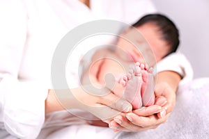 The mother held the baby in her hand. Mom holding small baby feet. Woman hands holding newborn baby feet