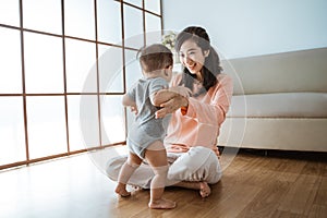 Mother help her baby to walk her first step