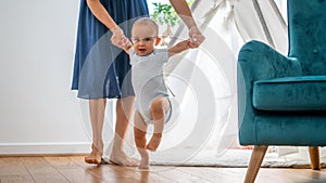 Mother Helping Baby Son To Take First Steps At Home