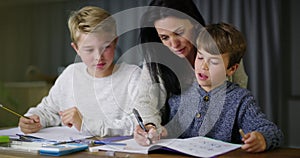 Mother helping boys with homework assignment, teaching and learning. Homeschool son and little brother learning