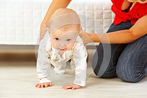 Mother helping cheerful baby learn to creep