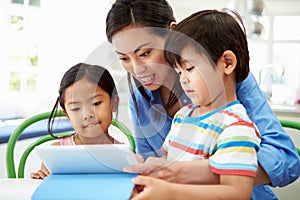 Mother Helping Children With Homework Using Digital Tablet