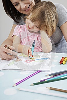 Mother helping daughter with colouring in book