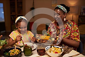 Mother Helping Daughter at Dinner Table