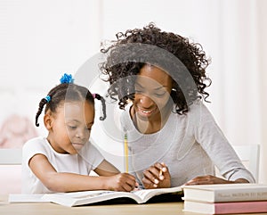 Mother helping daughter do homework in workbook