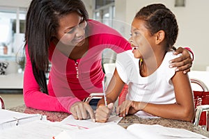 Mother Helping Daughter With Homework In Kitchen