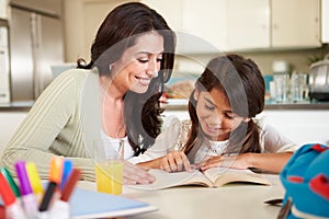 Mother Helping Daughter With Reading Homework At Table