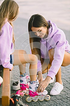 Mother helping daughter to dress rollers at park