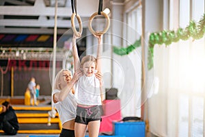 Mother helping daughter to play sports on gymnastic rings