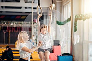 Mother helping daughter to play sports on gymnastic rings