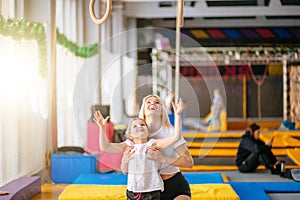 Mother helping daughter to play sports on gymnastic rings