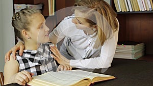 Mother helping her daughter do homework. Girl makes lessons, reading