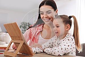 Mother helping her daughter with homework using tablet