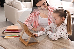 Mother helping her daughter with homework using tablet