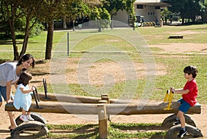 Mother Helping Her Kinds use a Teeter Totter photo