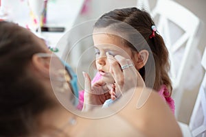 Mother helping her little girl with make up