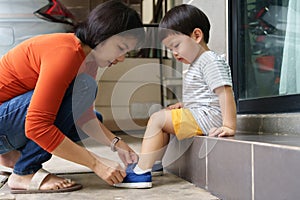 Mother helping her son put shoes on outdoors