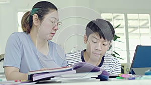 Mother helping her son to do his homework at home.