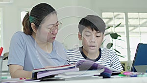 Mother helping her son to do his homework at home.