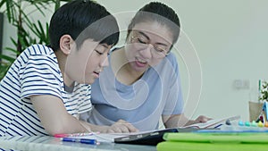 Mother helping her son to do his homework at home.