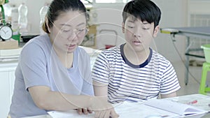 Mother helping her son to do his homework at home.