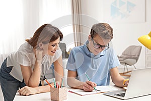 Mother helping her teenager son with homework