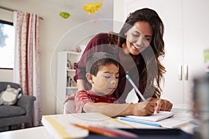 Mother Helping Son With Homework Sitting At Desk In Bedroom