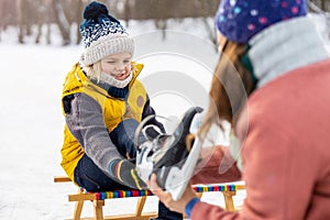 Mother helping son to put on his ice skates