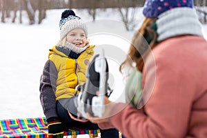 Mother helping son to put on his ice skates