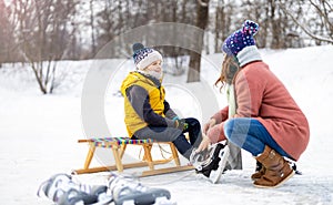 Mother helping son to put on his ice skates