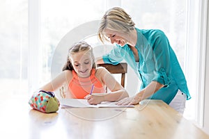 Mother helping teenaged girl with homework